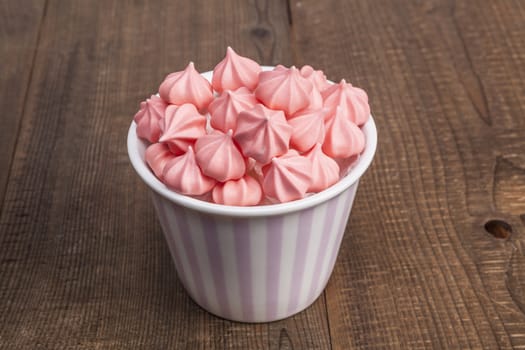 Pink sweets in a cup on wood table