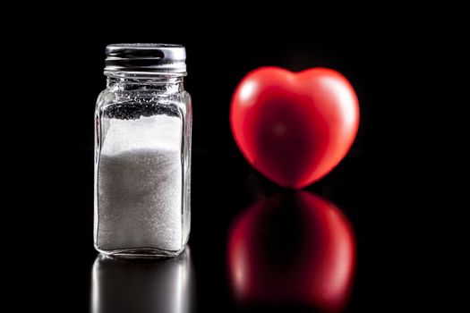 Salt and heart isolated on black background with reflection