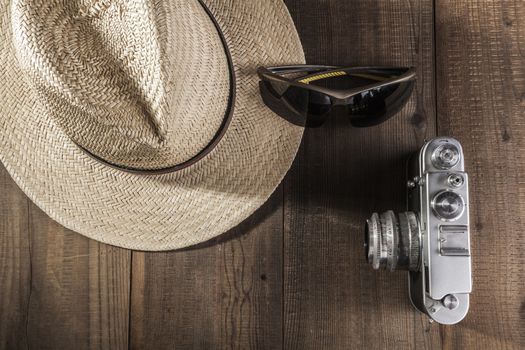 Hat, sunglasses and camera on wood table