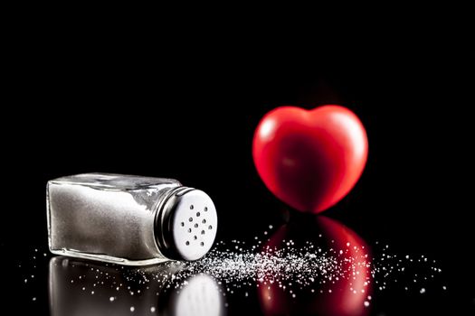 Salt and heart isolated on black background with reflection
