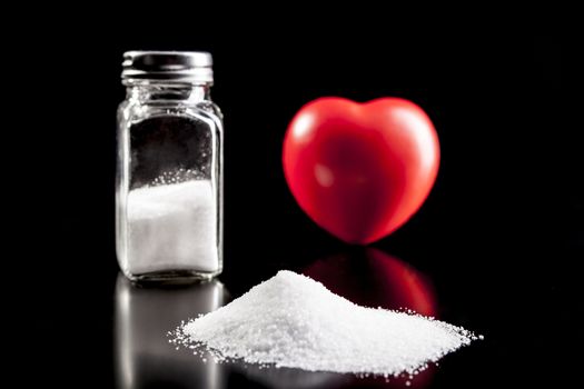 Salt and heart isolated on black background with reflection