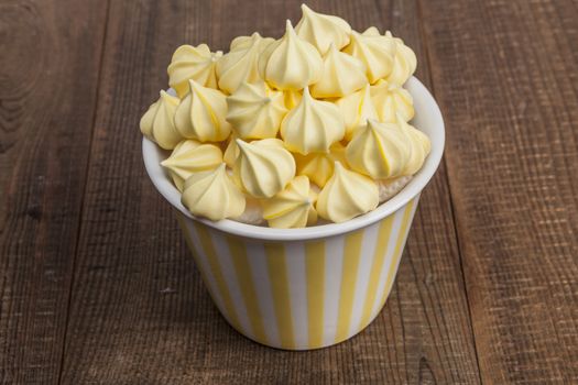 Yellow sweets in cup on wood table