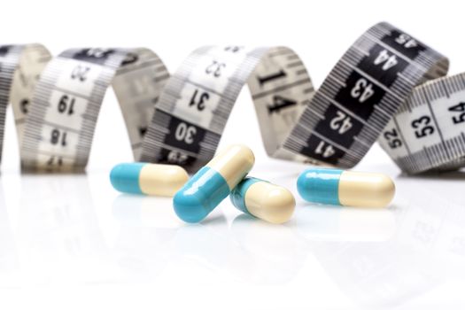 Blue Pills for Diet With Measuring Tape on White Background