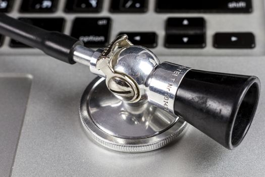 Black Stethoscope Closeup On Silver Laptop  With White Background