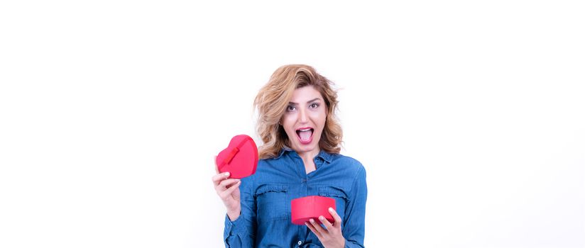 Attractive beautiful model woman gets surprised after opens heart shaped gift box.Valentine's Day concept in studio on a white background.
