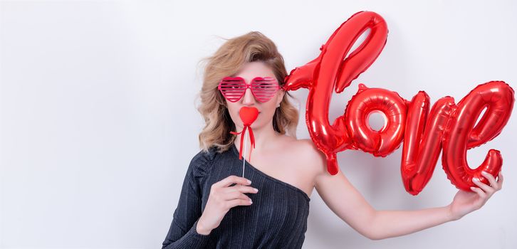 Attractive beautiful model woman holds love word letter shaped red balloon.Valentine's Day concept in studio on a white background.