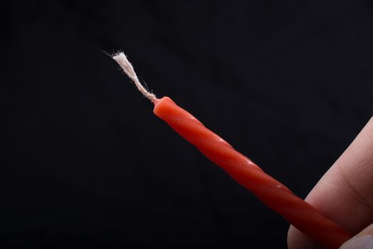 Colorful candle in hand on black background