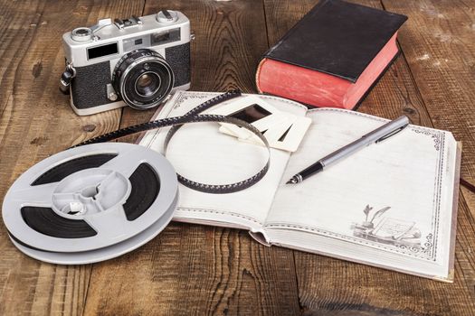 Old Camera With Film Roll and Notebook on Wood Table
