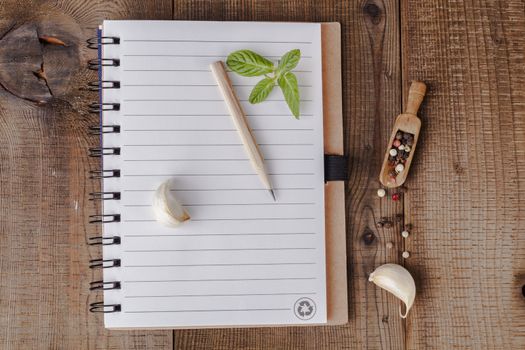 Spiral notebook with colored peppers and garlic on wood table