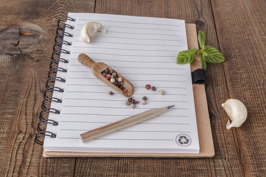 Spiral notebook with colored peppers and garlic on wood table