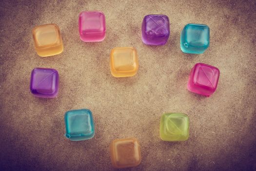 Fake colorful ice cubes on a brown background