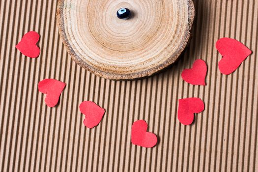 Bead on Piece of log with red paper hearts  on cardboard