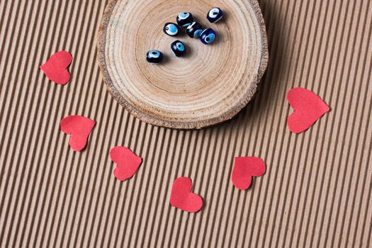 Beads on Piece of log with red paper hearts  on cardboard