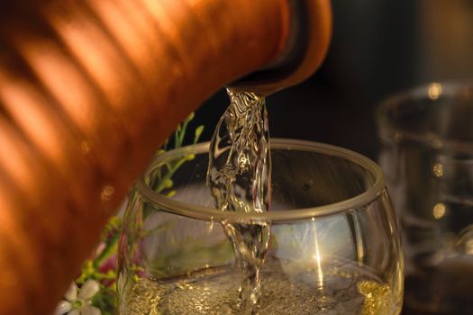 A close-up shot of white wine that is being poured into the wine glass during sunset.