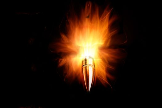 Rifle bullet with bright flames on black background