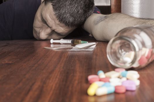Bruised hand with needle and pills on the table