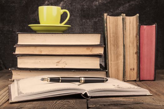 Old Books on Wood Table With Coffee and Open Notebook