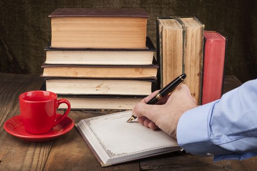 Old Books on Wood Table With Coffee Hand Writing in Open Notebook