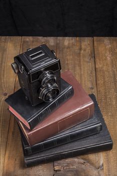 Old Camera Closeup on old Books and Brown Wood Background