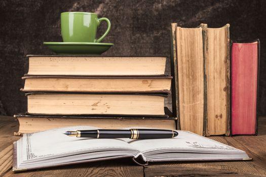 Old Books on Wood Table With Coffee and Open Notebook