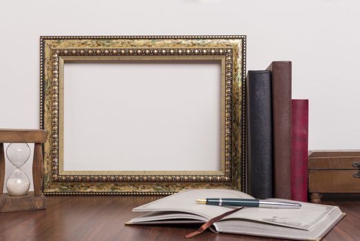 Landscape golden frame with books and hourglass on wood table