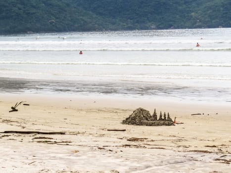 Sand castle landscape on beach with waves, in sunny day..