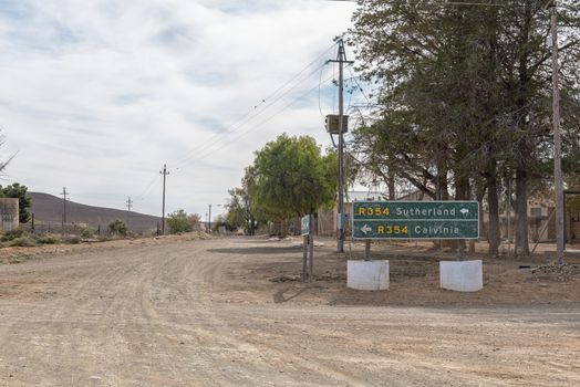 A street scene in Middelpos in the Northern Cape Province of South Africa. Directional signs and electricity infrastructure are visible