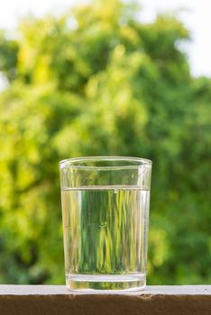 Glass of water, put on the balcony among the nature.