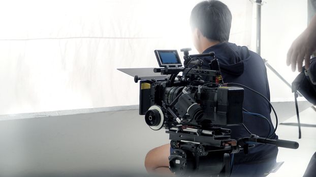 Behind video camera that recording online commercial or web film movie in the big studio production with professional equipment such as high resolution cam and monitors and LED light with crew team set