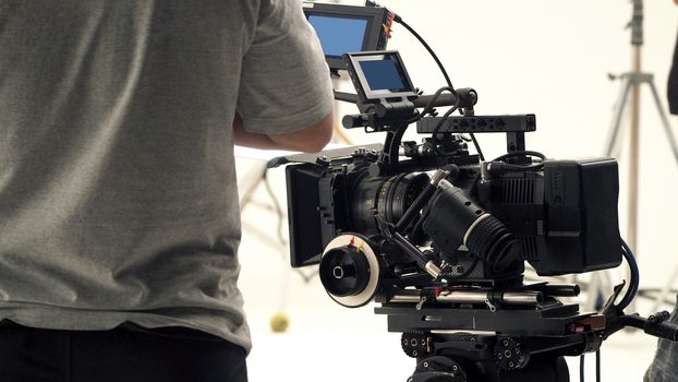 Behind video camera that recording online commercial or web film movie in the big studio production with professional equipment such as high resolution cam and monitors and LED light with crew team set