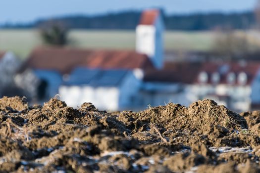 Closeup of a field with village Unterlappach in background in Bavaria, Germany in winter