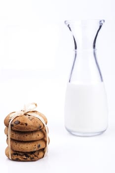 Glass of milk and chocolate chips cookies on white background