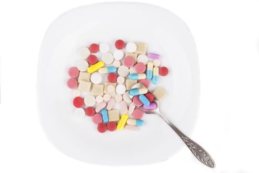 Colored pills medicine in a white plate isolated on white background