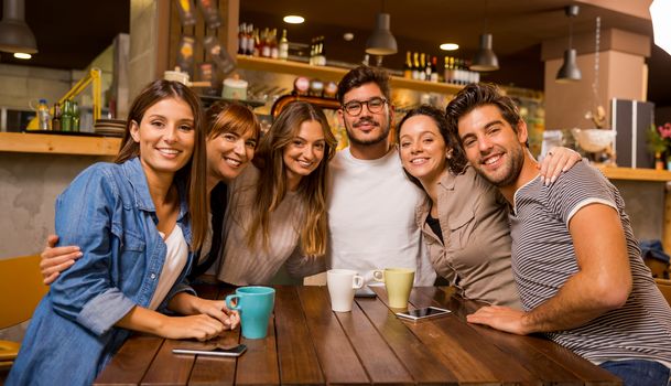 A group of friends looking to the camera at the cafe 