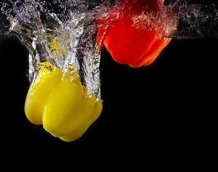 Vegetables tomato and paprika in water splash on black background