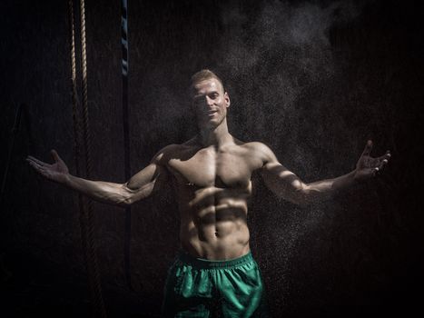 Shirtless man using chalk or magnesium powder in gym, clapping hands and creating cloud