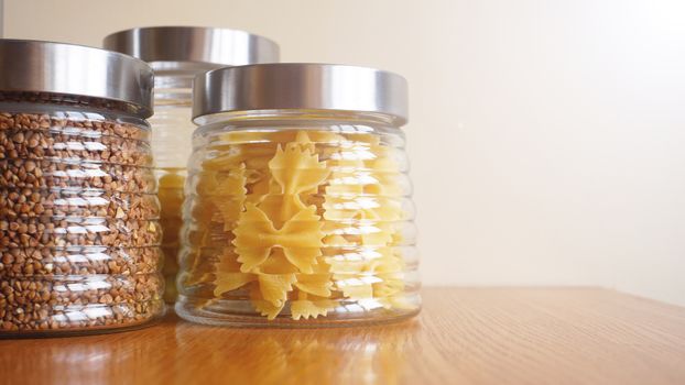 Pasta and bukwheat meals. Healthy cooking in glass jar containers on wooden table. Balanced dieting food.