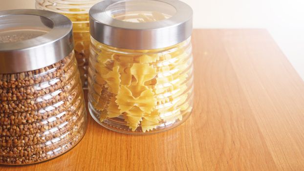 Pasta and bukwheat meals. Healthy cooking in glass jar containers on wooden table. Balanced dieting food.