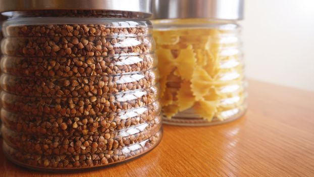 Pasta and bukwheat meals. Healthy cooking in glass jar containers on wooden table. Balanced dieting food.