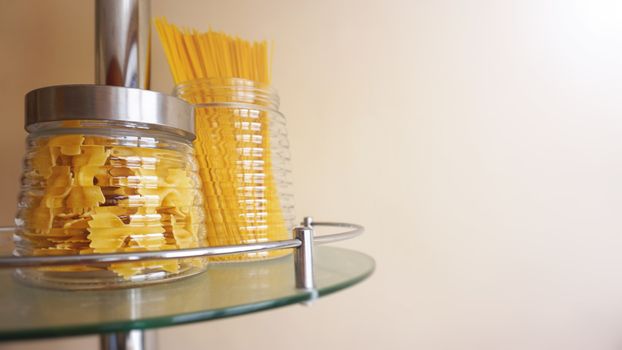 Pasta in a glass jar on light background. Free space for text