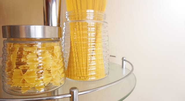 Pasta in a glass jar on light background. Free space for text