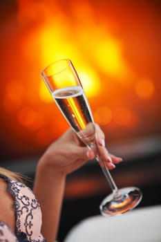 Champagne in woman hand on fireplace background