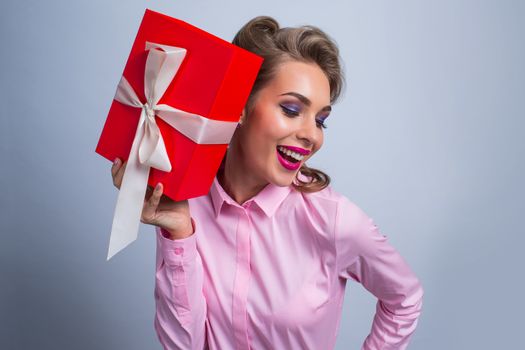 Happy beautiful funny woman holding red gift box with white ribbon