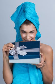 Beautiful young woman after shower with towel on head and creme on her face open beauty holiday gift