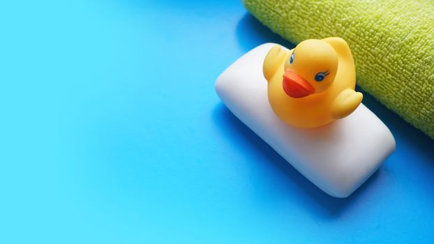 Terry towel, soap and yellow toy duck on a blue background. Flat lay photo, top view