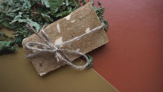 Organic handmade soap made of field herbs. Soap in a rope with dry grass on a golden and brown background