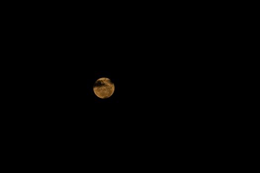 The moon behind clouds over a dark sky