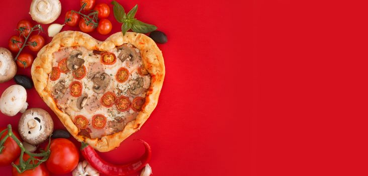 Pizza heart shaped with ham tomatoes and mushrooms on red background . Concept of romantic love for Valentines Day . Love food