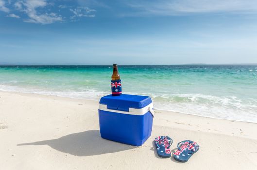 Chilling out on the beach, aussie style.  Thongs, esky and a cold beer on a beautiful beach in summer.  Thongs and cooler have the Australian flag printed on them