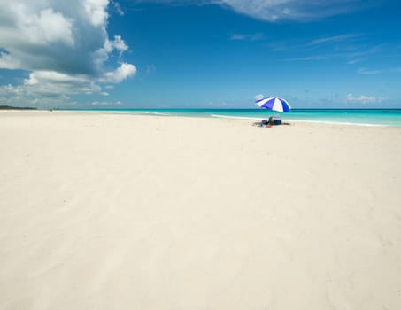 Wonderful  beach of Varadero during a sunny day, fine white sand and turquoise and green Caribbean sea,on the right one blue parasol,Cuba.concept  photo,copy space.